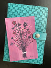 Floral bouquet painted on purple background sitting on turquoise book